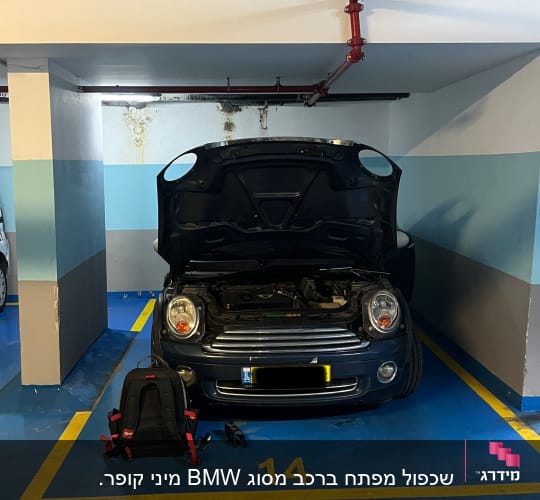 מכונית עם מכסה מנוע פתוח וחפצים על הרצפה